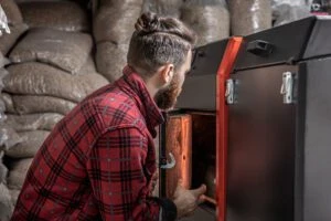 A man in a room with a solid fuel boiler, working on biofuel, economical heating.